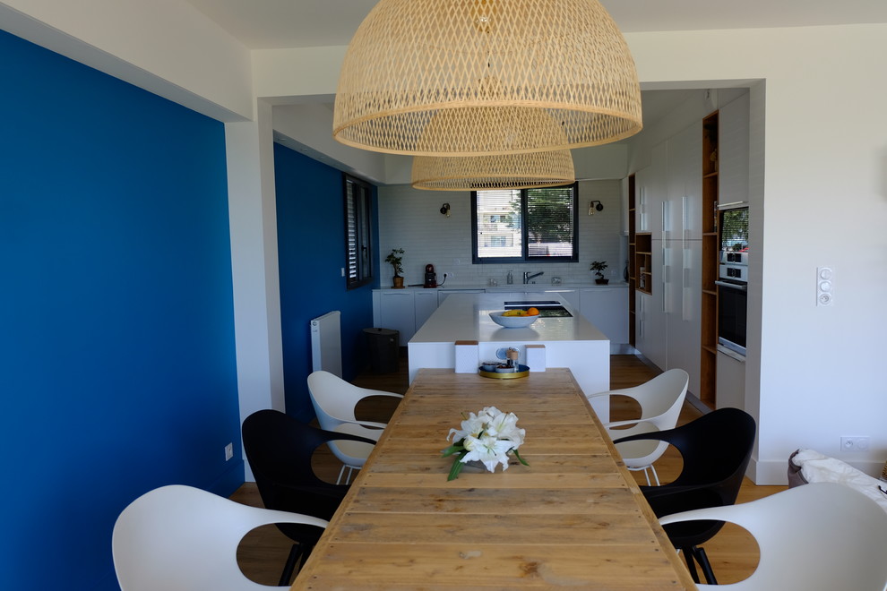 Salle à manger ouverte sur le salon?[Réalisation de salle à manger ouverte sur le salon With un évier intégré, un placard à porte plane, des portes de placard blanches, un plan de travail en surface solide, une crédence blanche, une crédence en céramique, un électroménager en acier inoxydable, un sol en contreplaqué, îlot, un sol jaune and un plan de travail blanc.]:[Réalisation de salles à manger ouvertes sur le salon With un évier intégré, un placard à porte plane, des portes de placard blanches, un plan de travail en surface solide, une crédence blanche, une crédence en céramique, un électroménager en acier inoxydable, un sol en contreplaqué, îlot, un sol jaune and un plan de travail blanc.]
