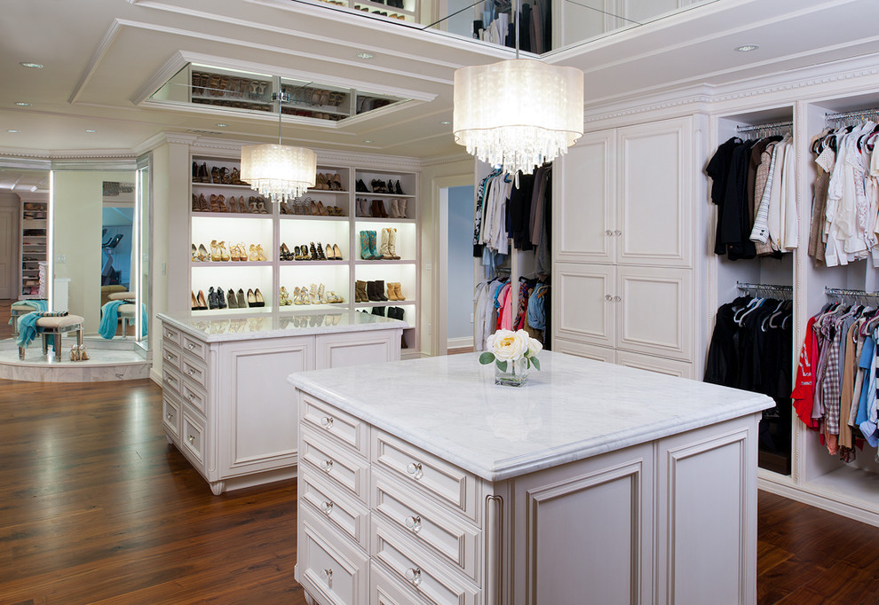 Photo of an expansive traditional women's dressing room in Other with white cabinets, light hardwood floors and recessed-panel cabinets.