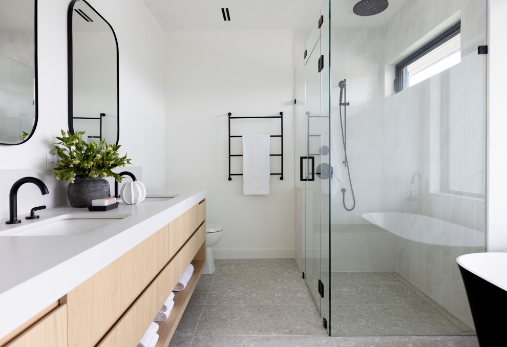 Mid-sized trendy master white tile gray floor and double-sink bathroom photo in Vancouver with flat-panel cabinets, light wood cabinets, white walls and a hinged shower door