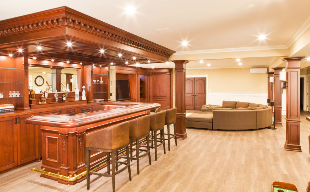 Inspiration for a large transitional walk-out basement in New York with a home bar, white walls, light hardwood floors, brown floor and vaulted.