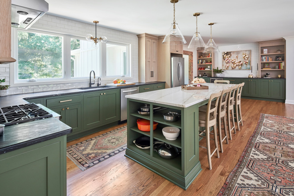 Example of a mid-sized cottage l-shaped medium tone wood floor and brown floor open concept kitchen design in Charlotte with a single-bowl sink, shaker cabinets, green cabinets, quartzite countertops, white backsplash, subway tile backsplash, stainless steel appliances, an island and white countertops