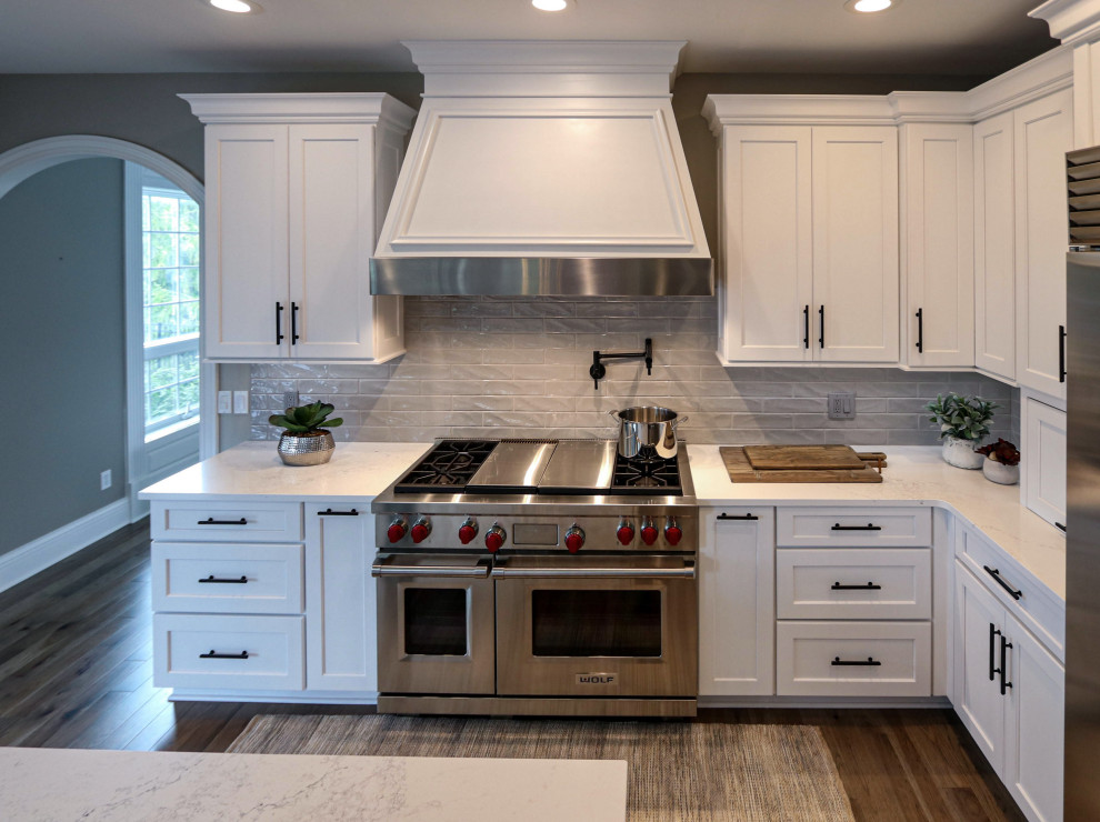 Example of a large transitional l-shaped medium tone wood floor and beige floor eat-in kitchen design in Cleveland with an undermount sink, flat-panel cabinets, white cabinets, quartz countertops, gray backsplash, glass tile backsplash, stainless steel appliances, an island and white countertops