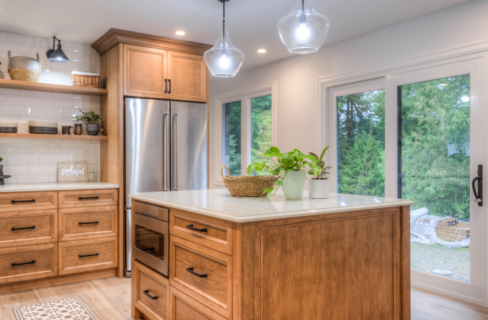 Kitchen - transitional l-shaped kitchen idea in Toronto with an undermount sink, shaker cabinets, light wood cabinets, white backsplash, stainless steel appliances, an island and white countertops