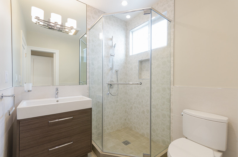 Inspiration for a small modern 3/4 bathroom in San Francisco with an integrated sink, flat-panel cabinets, medium wood cabinets, solid surface benchtops, a corner shower, a two-piece toilet, beige tile, beige walls and a hinged shower door.