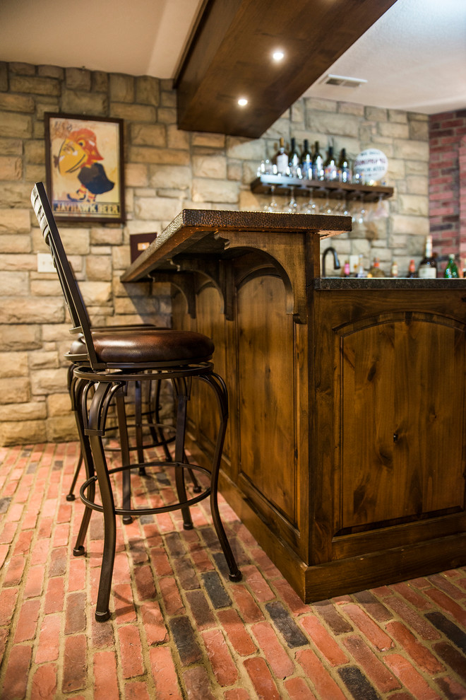 Inspiration for a mid-sized country u-shaped seated home bar in Kansas City with brick floors, red floor, an undermount sink, raised-panel cabinets, dark wood cabinets, red splashback and brown benchtop.