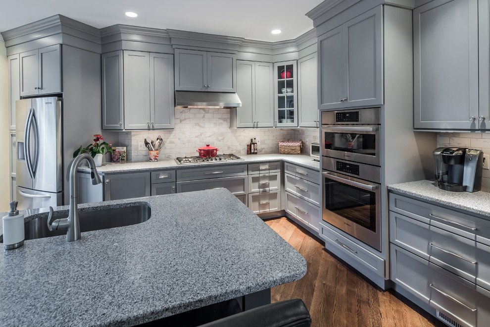 Example of a large transitional single-wall dark wood floor eat-in kitchen design in Boston with an undermount sink, flat-panel cabinets, gray cabinets, granite countertops, white backsplash, ceramic backsplash, stainless steel appliances and an island