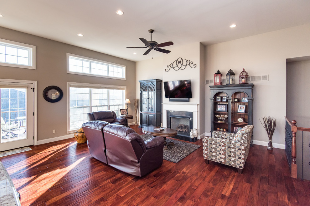 Mid-sized traditional open concept family room in St Louis with beige walls, medium hardwood floors, a standard fireplace, a stone fireplace surround and a wall-mounted tv.