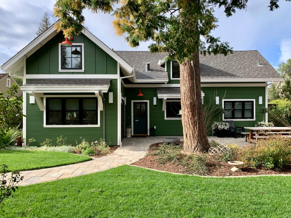 Cette image montre une façade de maison verte craftsman en bois et bardage à clin de taille moyenne et à un étage avec un toit à deux pans, un toit en shingle et un toit gris.