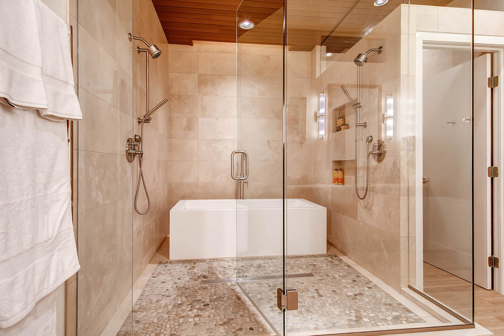 Design ideas for a contemporary bathroom in Denver with a freestanding tub, a double shower, beige tile and pebble tile floors.