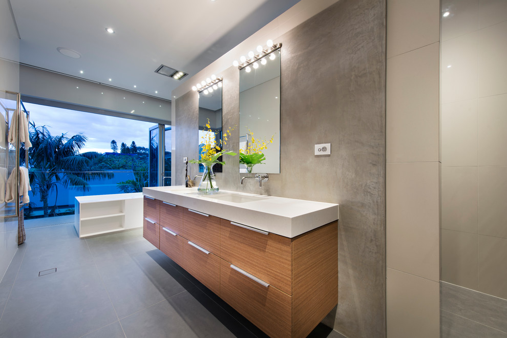 Photo of a contemporary bathroom in Perth with an undermount sink, flat-panel cabinets, medium wood cabinets, a freestanding tub and beige tile.