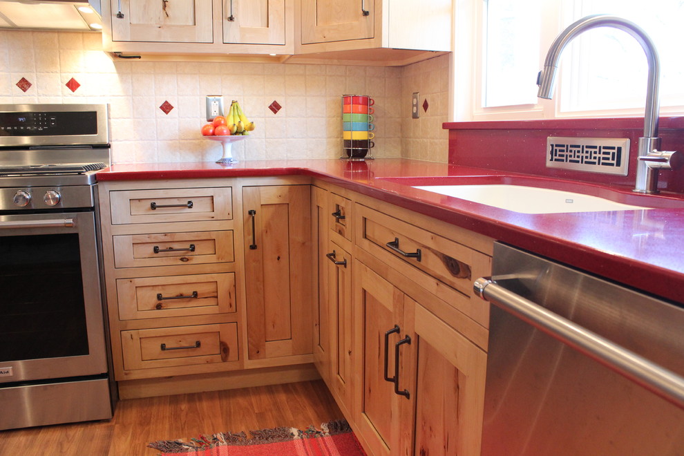 Example of a mid-sized mountain style l-shaped laminate floor enclosed kitchen design in Philadelphia with a double-bowl sink, shaker cabinets, light wood cabinets, quartz countertops, beige backsplash, ceramic backsplash, stainless steel appliances and no island