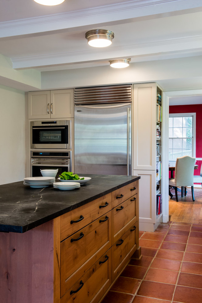 Eat-in kitchen - transitional l-shaped eat-in kitchen idea in DC Metro with a farmhouse sink, shaker cabinets, medium tone wood cabinets, soapstone countertops, black backsplash, ceramic backsplash and stainless steel appliances