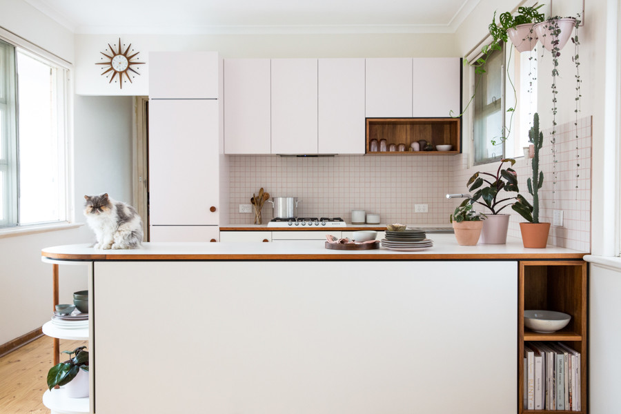 This is an example of a small midcentury u-shaped open plan kitchen in Adelaide with flat-panel cabinets, laminate benchtops, white splashback, ceramic splashback, white appliances and light hardwood floors.