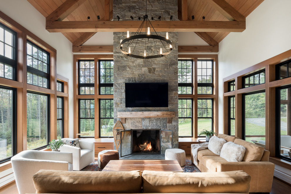 This is an example of a country open concept family room in Burlington with white walls, a metal fireplace surround, a wall-mounted tv, beige floor and exposed beam.