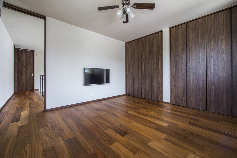 Imagen de armario vestidor minimalista con puertas de armario de madera en tonos medios, suelo de madera oscura, suelo marrón y papel pintado