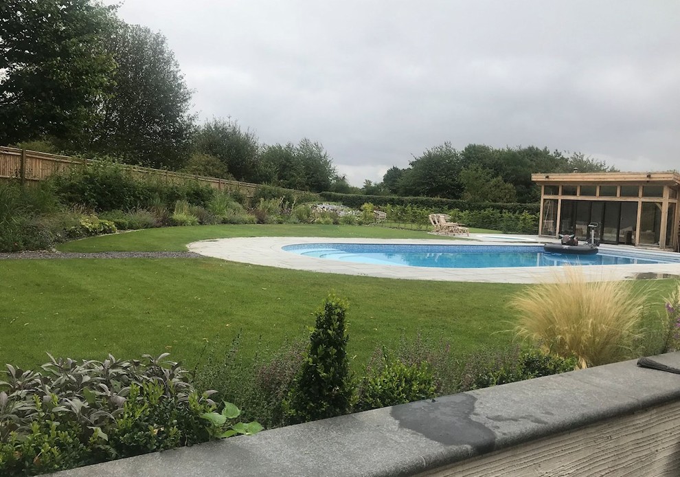 Large contemporary backyard full sun garden in Buckinghamshire with natural stone pavers for summer.