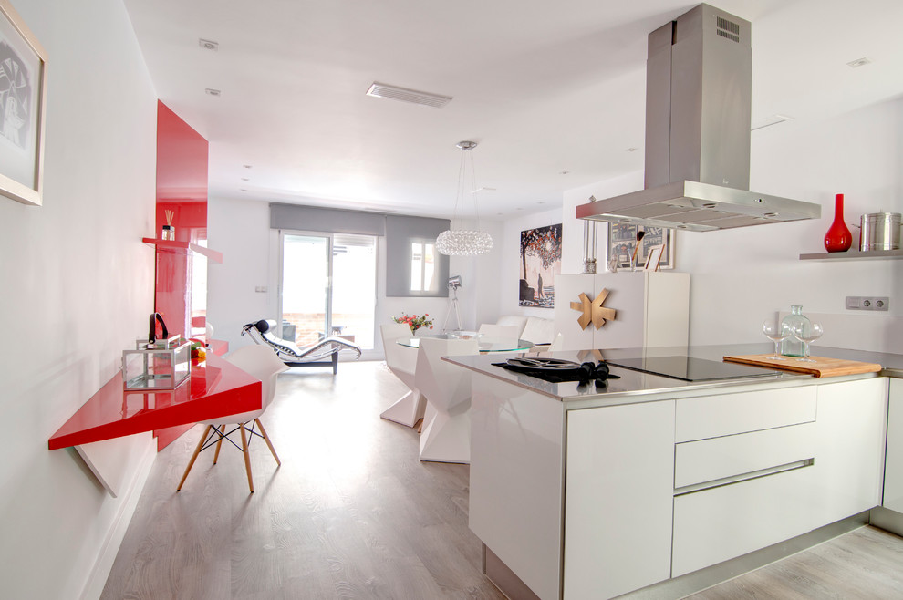 Design ideas for a mid-sized contemporary l-shaped open plan kitchen in Alicante-Costa Blanca with a single-bowl sink, flat-panel cabinets, white cabinets, stainless steel benchtops, white splashback, stainless steel appliances, medium hardwood floors and a peninsula.