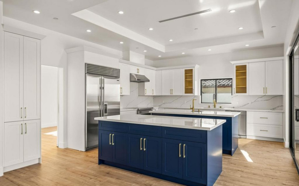 Aménagement d'une cuisine contemporaine avec des portes de placard bleues, une crédence blanche, 2 îlots et un plan de travail blanc.