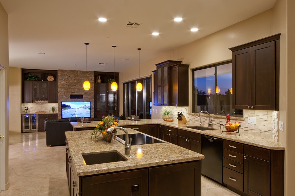 Photo of a large contemporary l-shaped eat-in kitchen in Phoenix with a drop-in sink, flat-panel cabinets, dark wood cabinets, granite benchtops, white splashback, ceramic splashback, stainless steel appliances, ceramic floors, with island and beige floor.