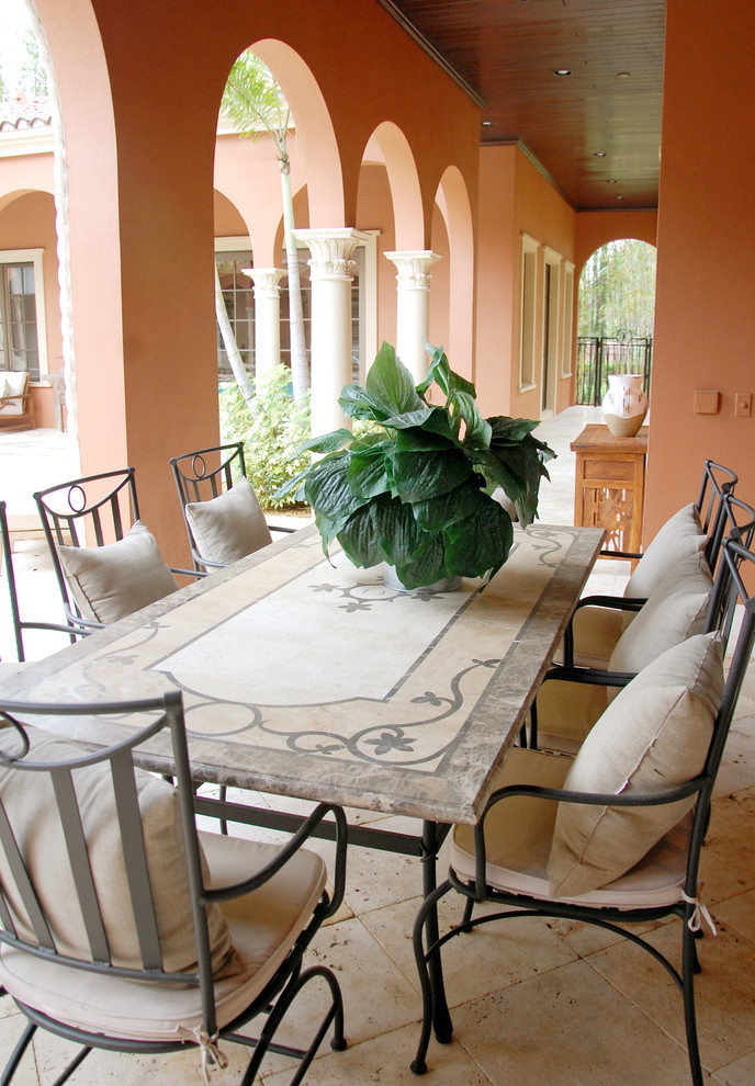Mid-sized mediterranean courtyard patio in Orlando with an outdoor kitchen, natural stone pavers and a roof extension.