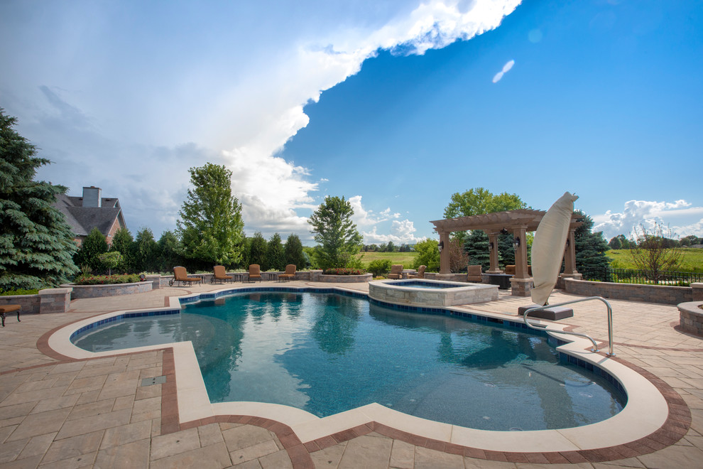 Design ideas for a mid-sized mediterranean backyard custom-shaped lap pool in Chicago with a hot tub and concrete pavers.