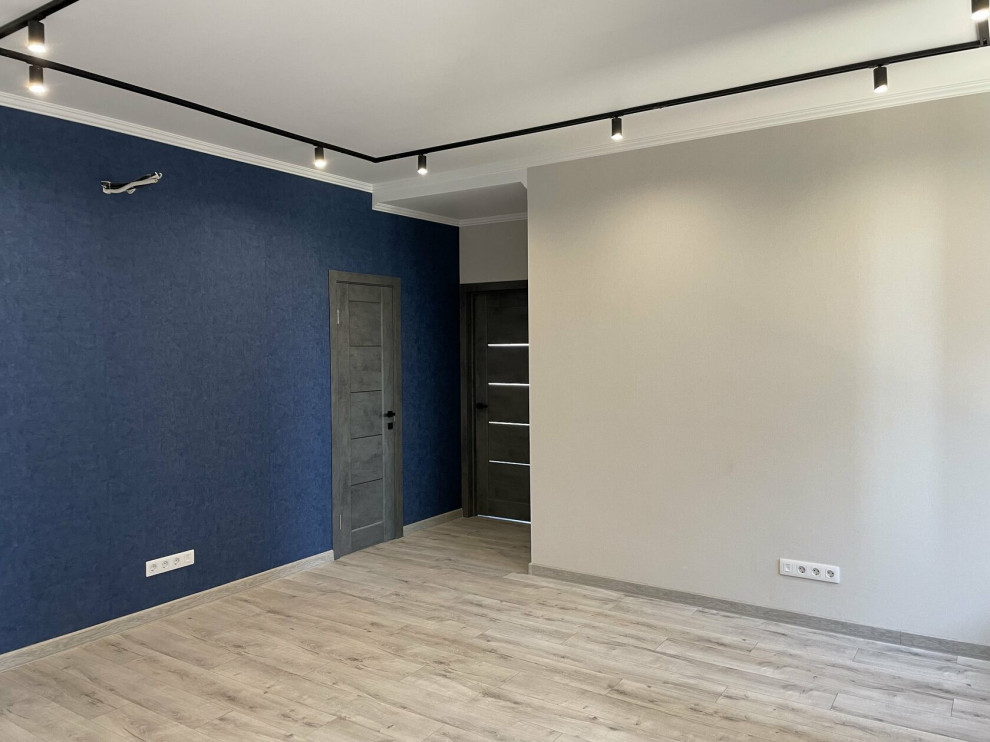 Imagen de salón abierto contemporáneo de tamaño medio con paredes azules, suelo laminado, suelo beige y papel pintado