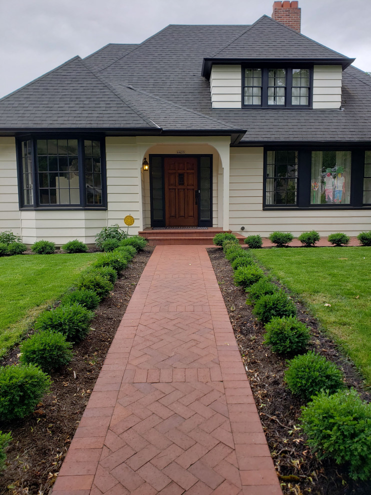 Photo of a mid-sized traditional front yard full sun formal garden for winter in Portland with with path and brick pavers.