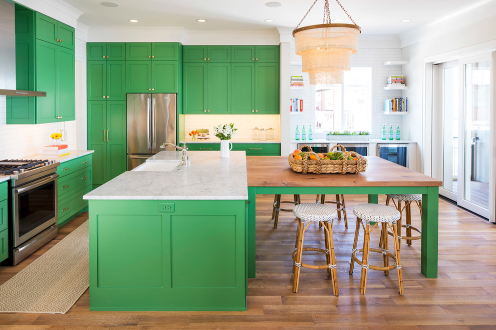 Large beach style u-shaped eat-in kitchen in Minneapolis with a farmhouse sink, shaker cabinets, green cabinets, marble benchtops, white splashback, ceramic splashback, stainless steel appliances, medium hardwood floors, multiple islands, brown floor and white benchtop.