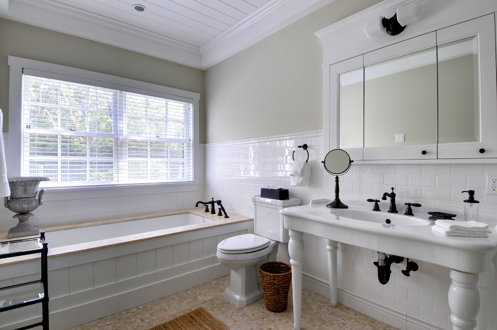 Photo of a large traditional master bathroom in Manchester with a console sink, subway tile, open cabinets, an undermount tub, white tile, an alcove shower, beige walls and limestone floors.