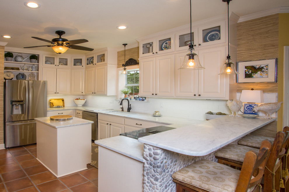 Mid-sized traditional u-shaped eat-in kitchen in Austin with a drop-in sink, raised-panel cabinets, white cabinets, marble benchtops, white splashback, subway tile splashback, stainless steel appliances, terra-cotta floors and with island.