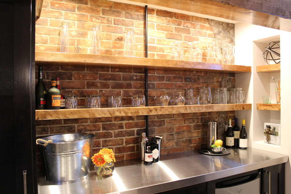 Inspiration for a modern home bar in Calgary with shaker cabinets, dark wood cabinets, stainless steel benchtops and brick splashback.
