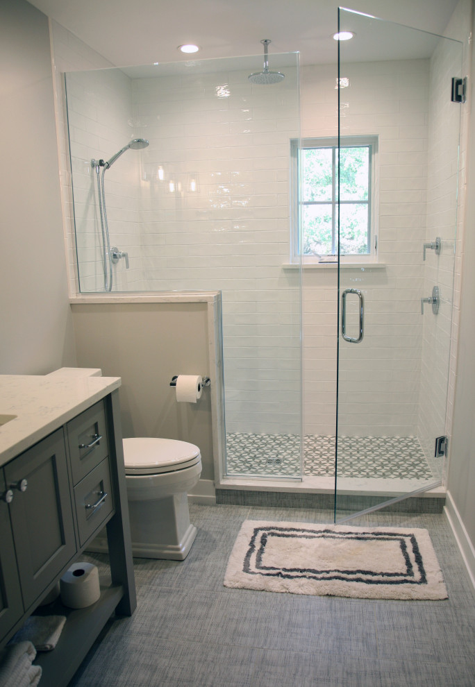 Cette photo montre une salle de bain bord de mer de taille moyenne avec un placard à porte shaker, des portes de placards vertess, WC séparés, un carrelage blanc, un carrelage métro, un mur beige, un sol en carrelage de porcelaine, un lavabo encastré, un plan de toilette en quartz modifié, un sol gris, une cabine de douche à porte battante, un plan de toilette blanc, meuble simple vasque et meuble-lavabo suspendu.