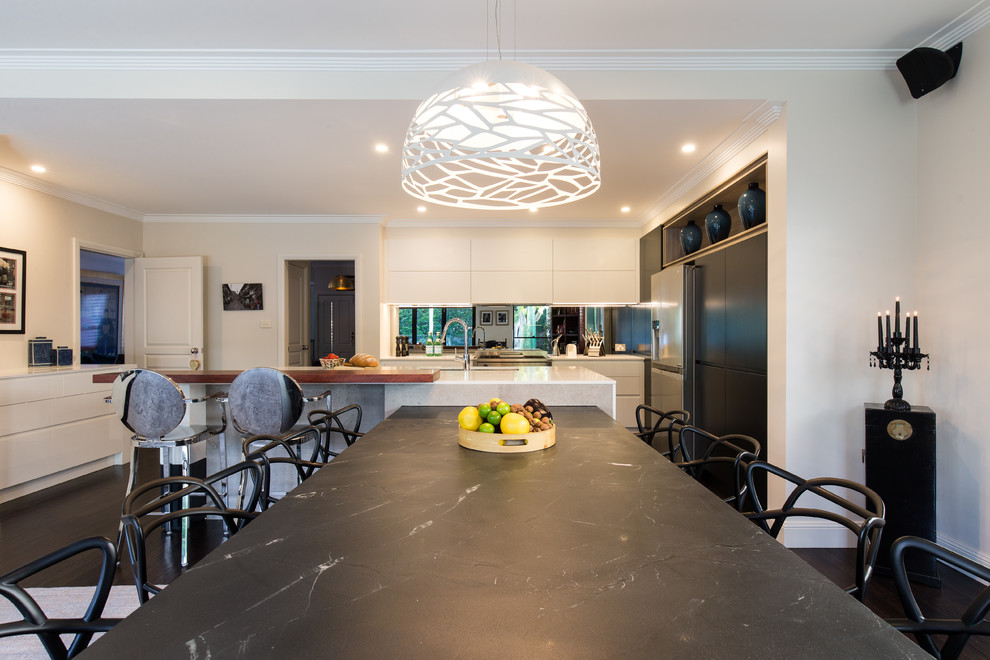 Photo of a large contemporary l-shaped kitchen in Sydney with an undermount sink, white cabinets, quartz benchtops, mirror splashback, dark hardwood floors, multiple islands, black floor and black benchtop.