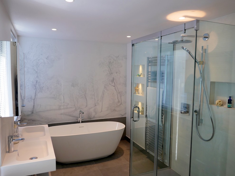 Photo of a large contemporary master bathroom in London with flat-panel cabinets, white cabinets, a freestanding tub, a wall-mount toilet, white tile, porcelain tile, white walls, porcelain floors, a drop-in sink, engineered quartz benchtops, grey floor and white benchtops.