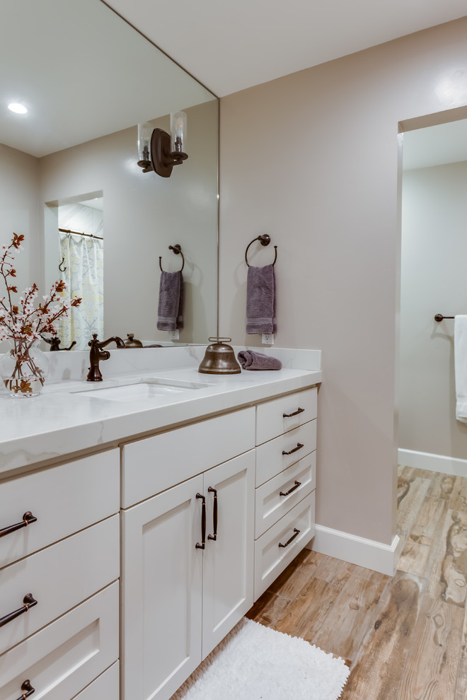 This is an example of a mid-sized transitional master bathroom in Sacramento with shaker cabinets, white cabinets, an alcove shower, beige walls, light hardwood floors, an undermount sink, brown floor, a shower curtain, grey benchtops and marble benchtops.