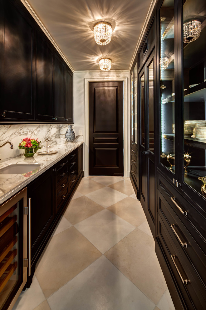 Traditional galley kitchen pantry in Houston with an undermount sink, recessed-panel cabinets, black cabinets, marble benchtops, marble splashback, no island, beige floor, grey splashback and grey benchtop.
