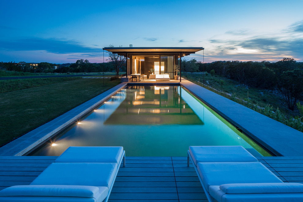 Design ideas for a large contemporary backyard rectangular lap pool in Austin with concrete slab and a pool house.