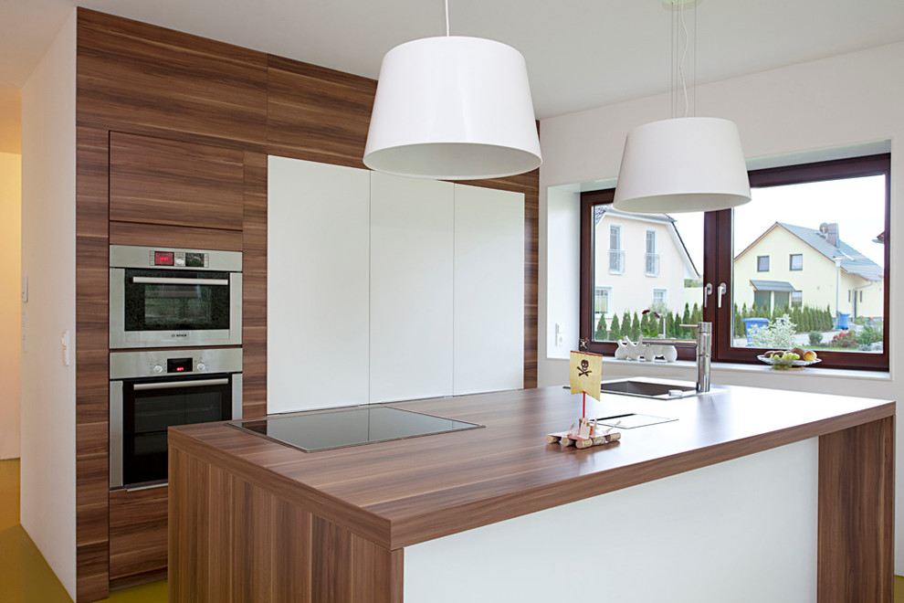 Design ideas for a mid-sized contemporary separate kitchen in Leipzig with with island, a drop-in sink, flat-panel cabinets, dark wood cabinets, wood benchtops and panelled appliances.