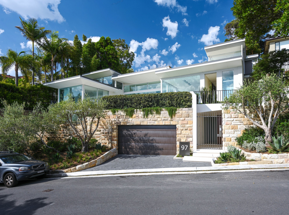 Großes, Dreistöckiges Modernes Einfamilienhaus mit Backsteinfassade, weißer Fassadenfarbe, Flachdach, Blechdach und grauem Dach in Sydney