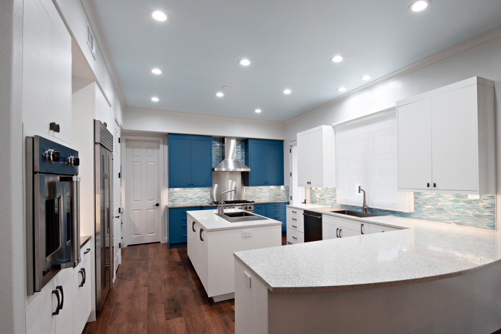 Photo of a large contemporary u-shaped eat-in kitchen in San Diego with a drop-in sink, flat-panel cabinets, white cabinets, stainless steel benchtops, blue splashback, mosaic tile splashback, stainless steel appliances, medium hardwood floors, with island and white benchtop.