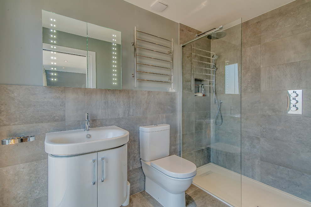 Small contemporary master bathroom in Surrey with flat-panel cabinets, beige cabinets, an open shower, a two-piece toilet, gray tile, grey walls, porcelain floors and a wall-mount sink.