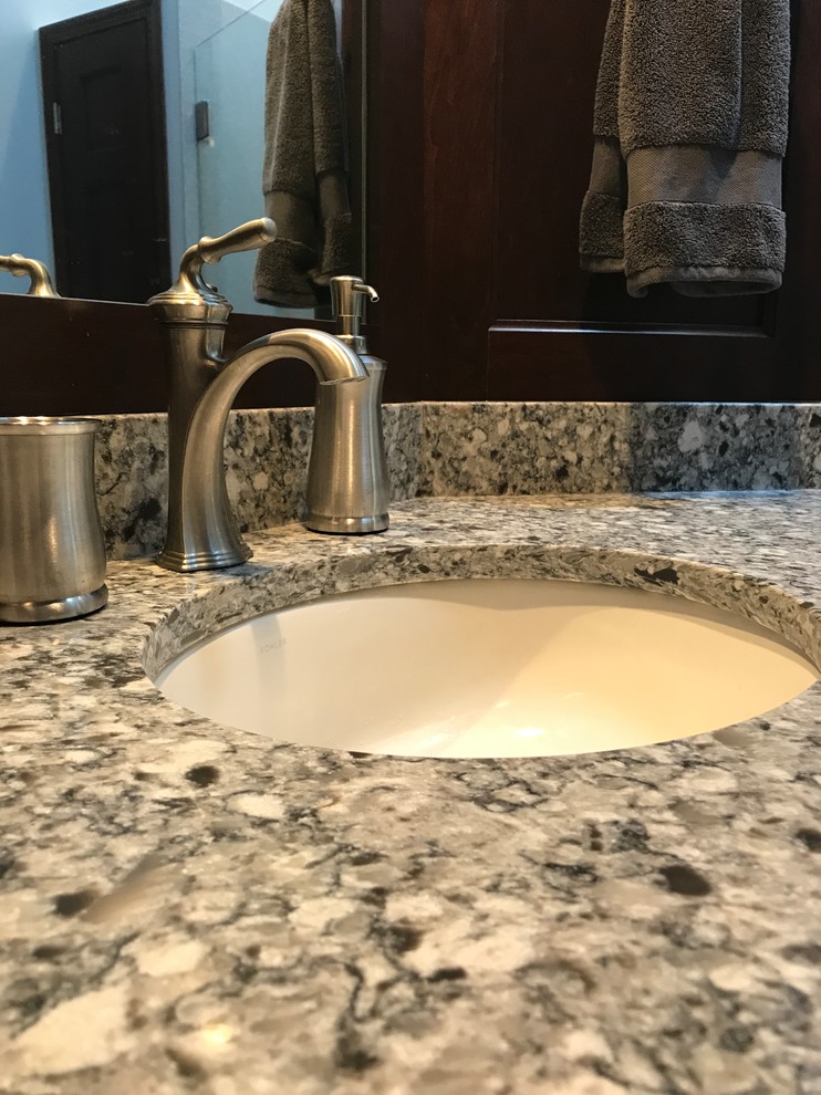 Example of a mid-sized transitional master gray tile gray floor bathroom design in Milwaukee with shaker cabinets, dark wood cabinets, a two-piece toilet, gray walls, an undermount sink and quartz countertops