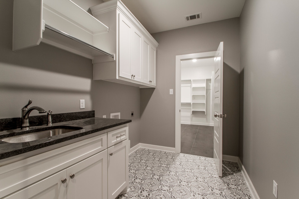 Large modern single-wall dedicated laundry room in Little Rock with an undermount sink, shaker cabinets, white cabinets, quartz benchtops, grey walls, ceramic floors, a side-by-side washer and dryer, multi-coloured floor and black benchtop.