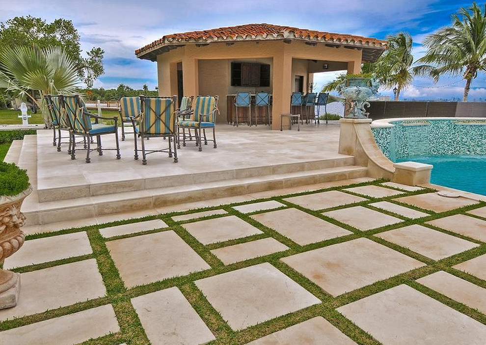 This is an example of a large mediterranean backyard rectangular pool in Miami with a water feature and tile.
