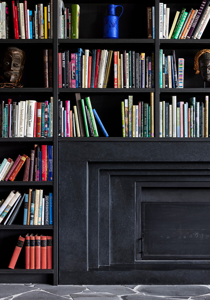Foto di un grande studio minimal con libreria, pareti nere, camino classico e cornice del camino in metallo