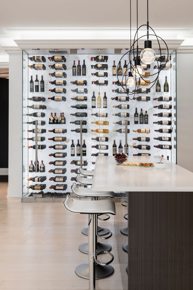 Photo of a mid-sized modern wine cellar in Toronto with light hardwood floors, display racks and beige floor.
