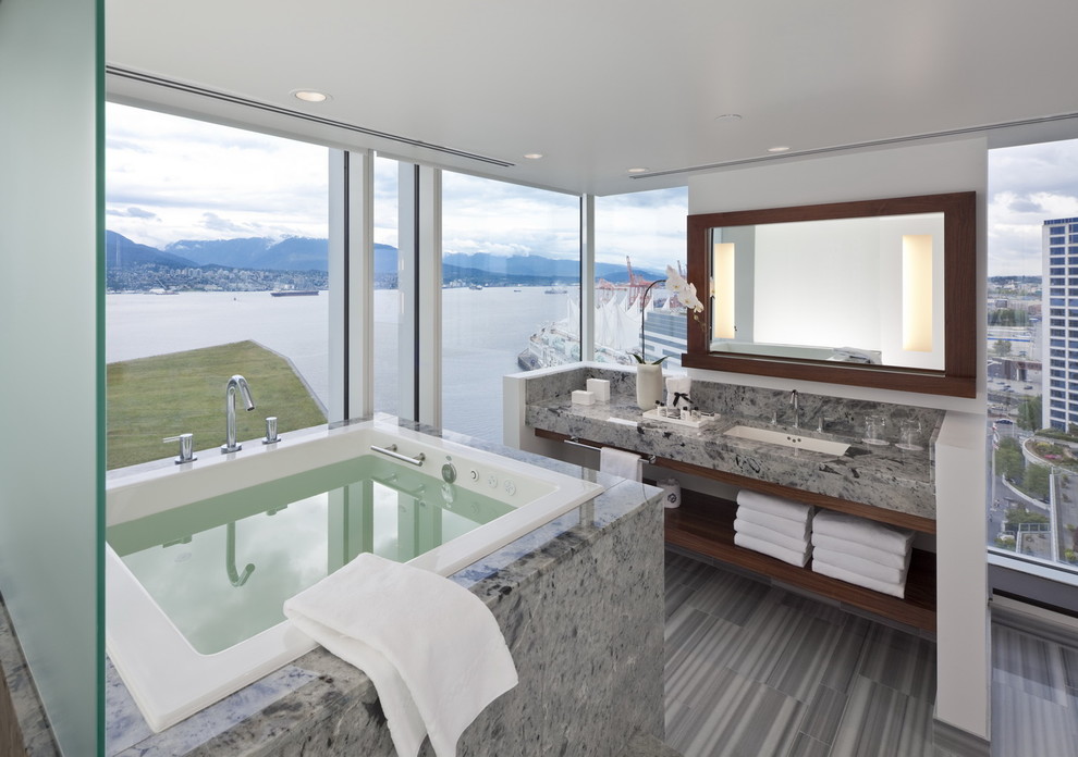 Mid-sized contemporary master bathroom in Vancouver with an undermount sink, open cabinets, dark wood cabinets, a drop-in tub, gray tile, a two-piece toilet, white walls, porcelain floors and granite benchtops.