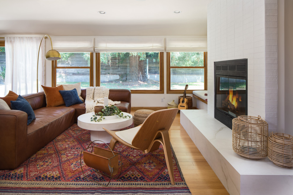 Mid-sized scandinavian formal open concept living room in Los Angeles with white walls, bamboo floors, a standard fireplace, a tile fireplace surround, no tv and yellow floor.