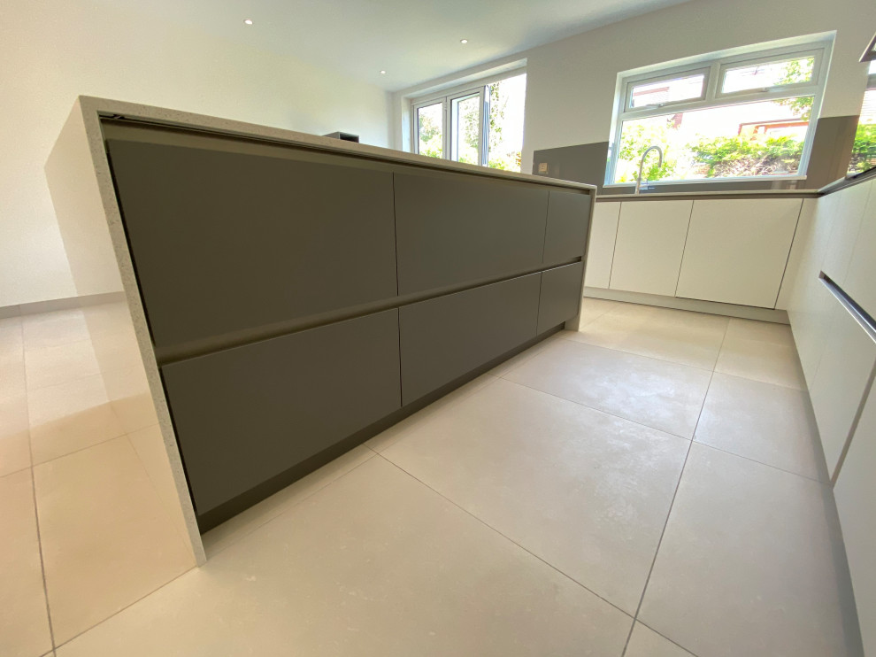 This is an example of a large contemporary l-shaped open plan kitchen in London with flat-panel cabinets, white cabinets, quartzite benchtops, brown splashback, glass sheet splashback, black appliances, with island and white benchtop.