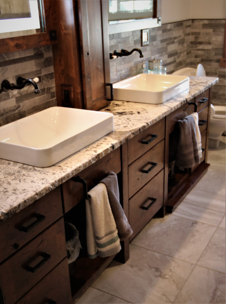 Inspiration for a large rustic gray tile and stone tile bathroom remodel with furniture-like cabinets, dark wood cabinets, a vessel sink, granite countertops and white countertops